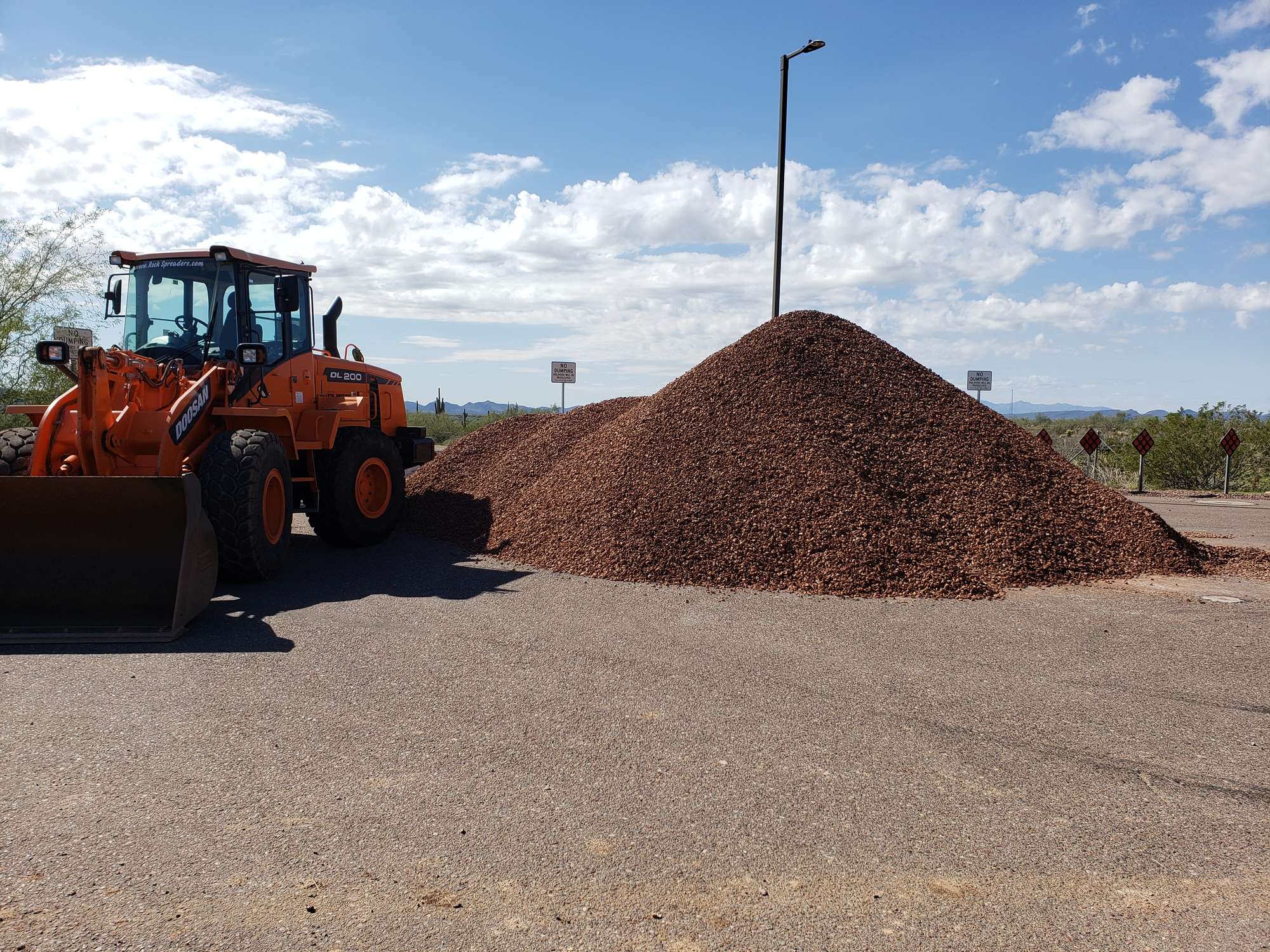 Wheel loader beside a large pile of red decorative granite on an Arizona job site