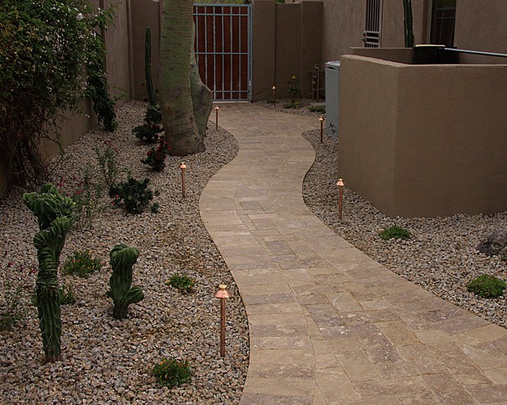 Curved paver walkway bordered with decorative gravel and cacti at an Arizona home entrance