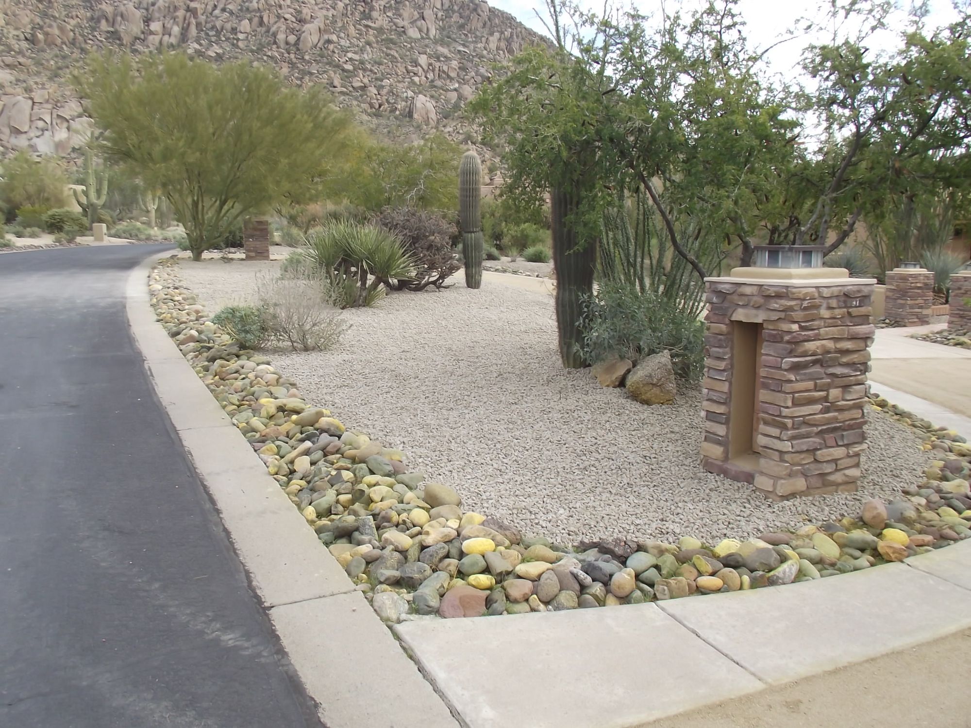 Decomposed granite streetscape with a river-rock border along an Arizona HOA community road