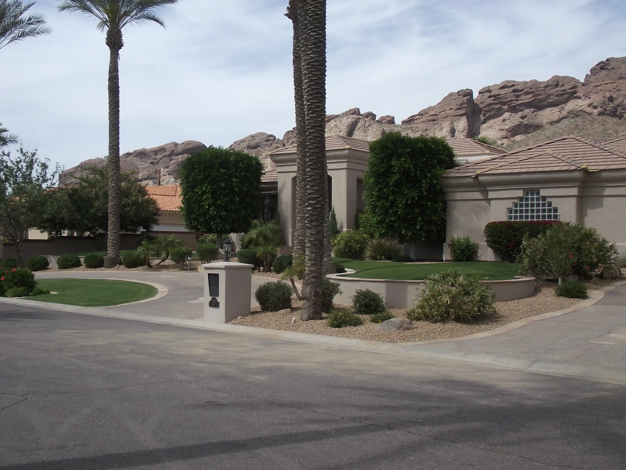 Upscale Arizona home front yard with palms, gravel, and a red-rock mountain backdrop