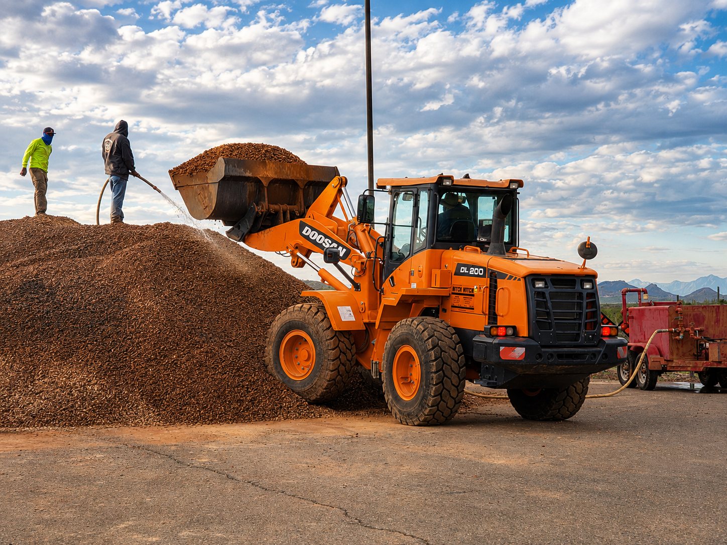 Rock Spreaders crew loading and wetting down a large pile of decorative granite with a Doosan wheel loader at an Arizona job site